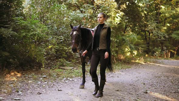 Slowmotion Shot Beautiful Young Female Jokey is Walking with a Stunning Brown Horse with White Spot alt