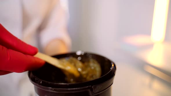 Handyman in Red Gloves Stirs Sugar Paste Before Removing Unwanted Hair alt
