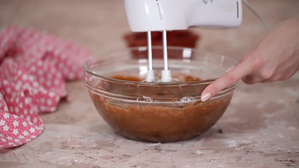 Mixer beating chocolate batter in bowl.