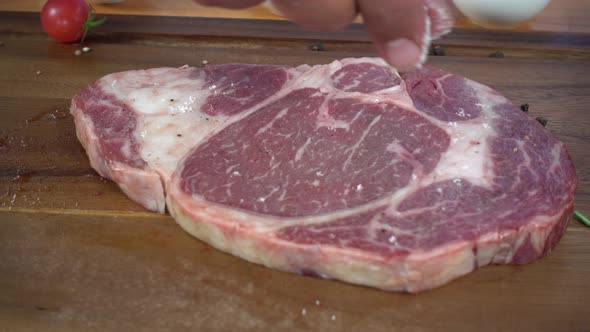 Chef cook season fresh chunk of deli piece of beef with sea salt and grounded spicy peppers. alt