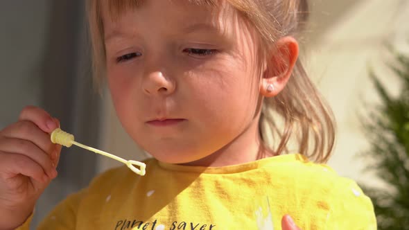 Little Girl Blows Soap Bubbles Outdoor in Summer