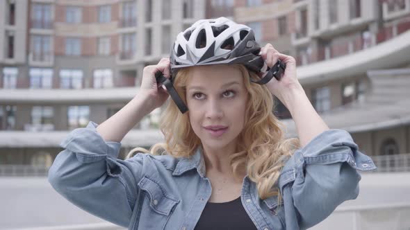 Portrait Cute Blond Woman Putting a Bike Helmet on Her Head and Riding Her Bicycle alt
