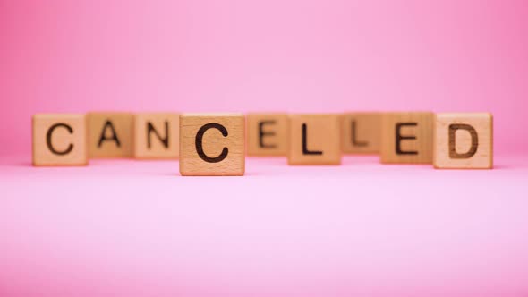 CANCELLED Word Made with Building Blocks, Business Concept. Word CANCELLED on Pink Background