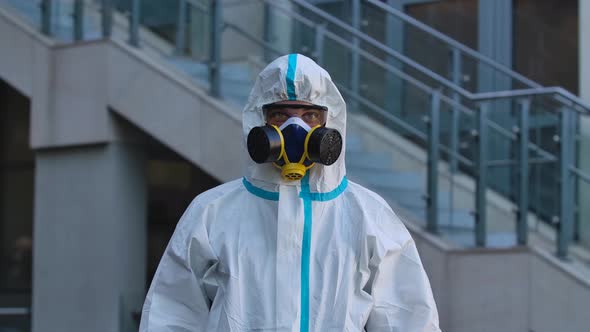 Portrait of a Young Man in a Protective Suit, Respirator, Gloves and Safety Glasses Looks Into the alt