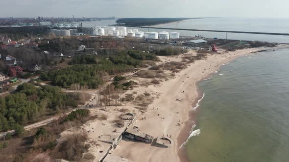 AERIAL: Melnrage Beach with Klaipeda City and Ship Port Visible in a Distance on a Cloudy Day