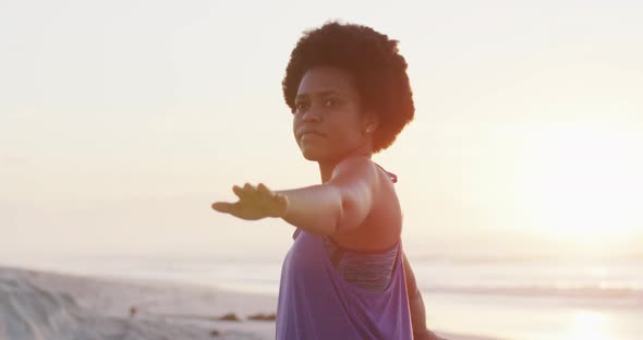 Happy african american woman practicing yoga on sunny beach alt