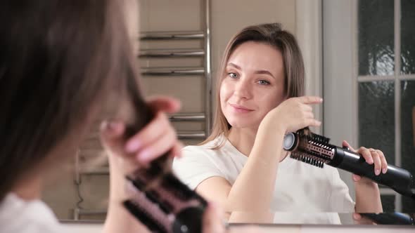 Woman Drying Her Hair Styling in the Bathroom Near Mirror alt
