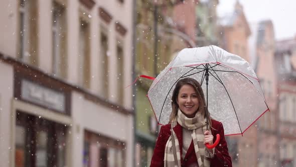 adult girl in red coat and scarf with umbrella white snowfall