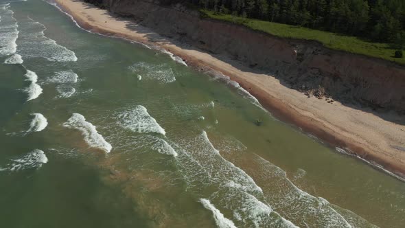 Scenic Slow Motion Drone Fligh Down Above Turquoise Baltic Sea with Waves and Sand Cliff alt