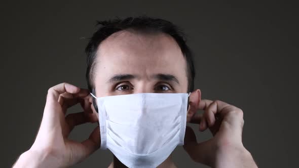 Caucasian man wearing a white medical mask for protection against contagious disease, coronavirus