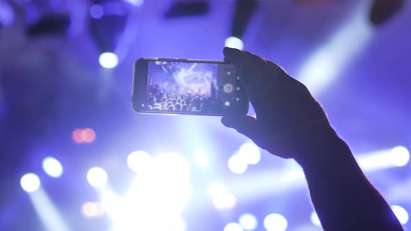 Man Hands Recording Video of Live Music Concert with Smartphone at Night