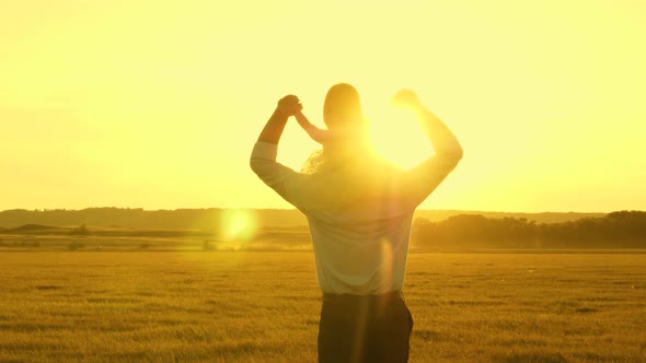 Concept of a Happy Childhood. Dad with Little Daughter on Their Shoulders Walk and Watch Beautiful alt