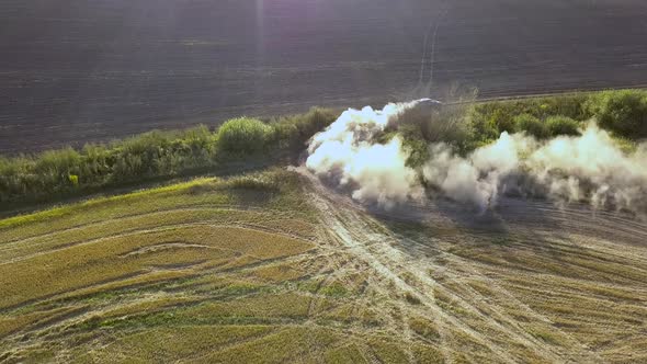 Top down aerial view of fast driving car on dirt road leaving cloud of dust behind. alt