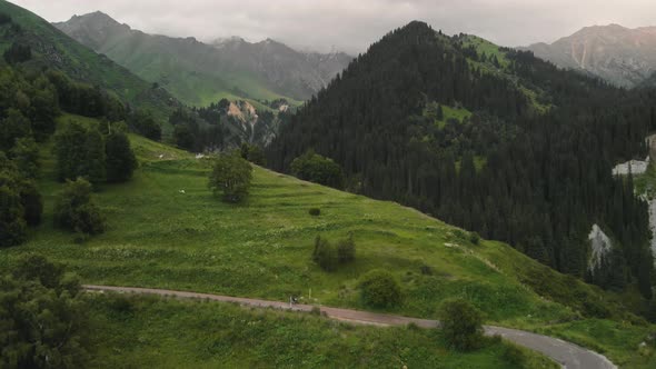 Man Ride Bicycle on the Mountain Road Aerial Shot alt