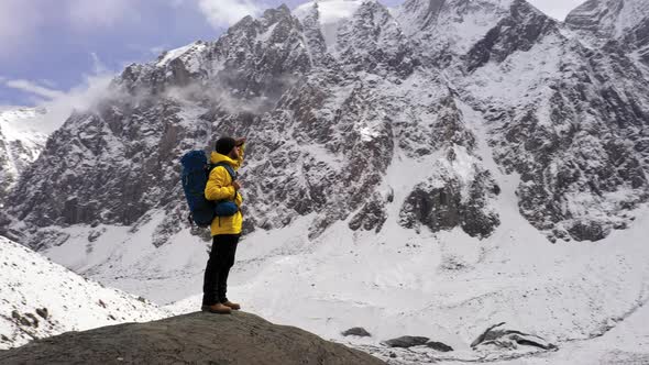 Tourist on Mountain Top. Sport and Active Life. Hiker with Backpack Standing on Top of a Mountain alt