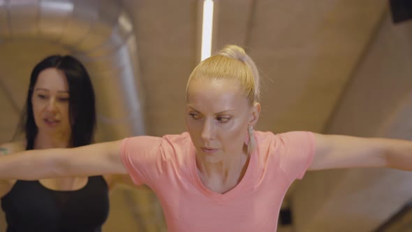 Camera Zooming Out From Serious Sportswoman Lifting Dumbbells with Personal Trainer Adjusting Her alt