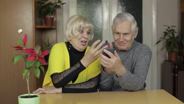 Pretty Mature Senior Couple Grandparents Enjoy Online Shopping on Phone at Home alt