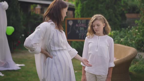 Displeased Adolescent Girl Looking at Pregnant Belly with Dissatisfied Facial Expression As Woman alt
