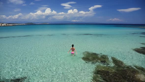 Young girl stand in  water on beach in Halkidiki, Greece in summertime alt