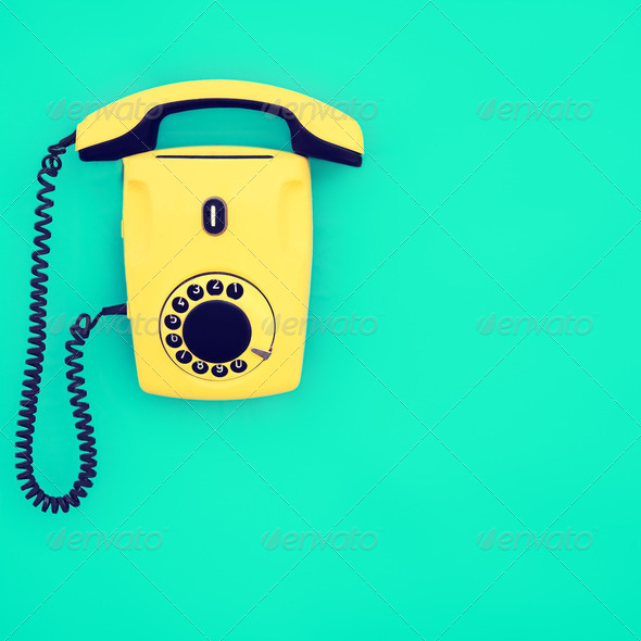 yellow retro telephone on a blue background - Stock Photo - Images