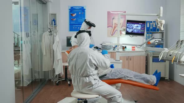 Orthodontist in Protection Suit Explaining Dental Surgery alt