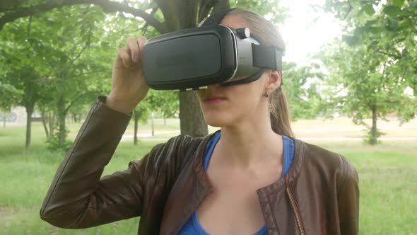 Oung Cheerful Girl Uses A Modern Virtual Reality Helmet In The Park