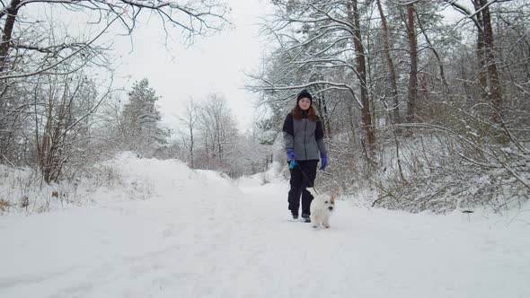 Young Beautiful Caucasian Girl And Dog Running Together In Snowy Day alt