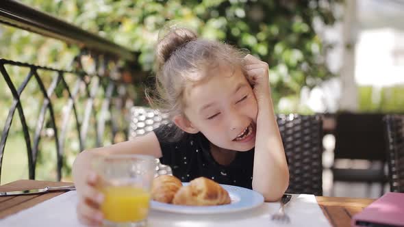 Adorable Girl Having Breakfast at Outdoor Cafe alt