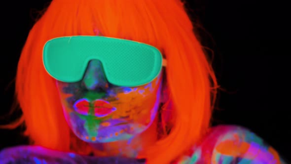 Beautiful Model Woman in Wig and Glasses with Colorful Bright Fluorescent Makeup in Neon Light