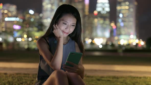 Woman looking at cellphone at night  alt