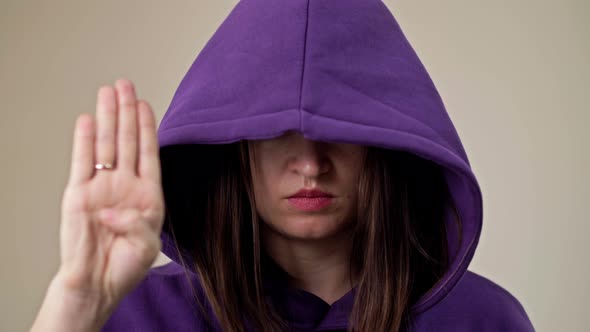 Woman Covering Her Face with a Hood Demonstrates a Gesture Indicating a Person's Need for Help alt