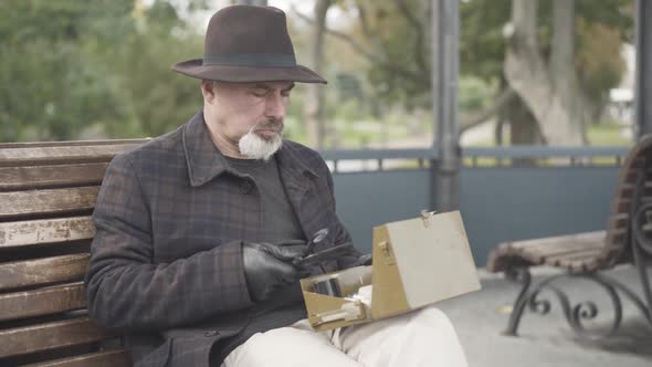 Serious Handsome Caucasian Spy or Intelligencer Examining Box with Novichok Using Magnifying Glass alt