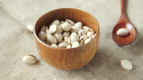 Pouring Pistachios Nut on in Wooden Bowl alt