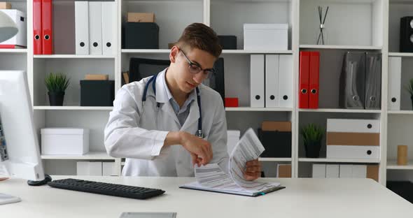 Young Doctor Checking Documents at Workplace