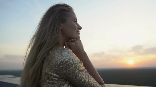 Inspired Woman in Shiny Dress Enjoying City View From Terrace at Home Party