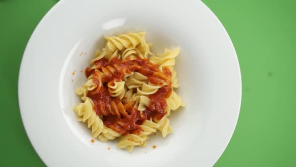 Vertical video: parmesan cheese falls on pasta in a plate alt