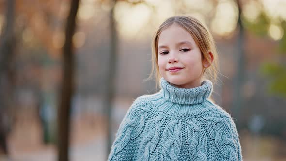 Little Girl Looking at you and Smiling Showing Her White Teeth While Posing in Autumn Park alt