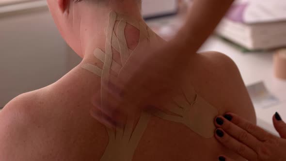 Kinesiologist Applying Kinesiology Tapes on Female Back alt