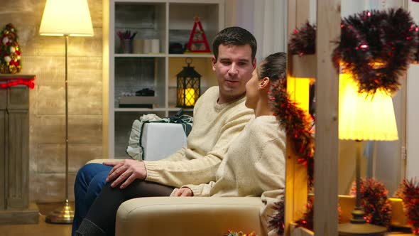 Romantic Young Couple Sitting on the Couch on Christmas Day alt