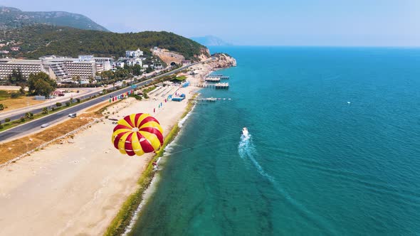 The red-yellow parachute is shading behind the boat. Parasailing in Turkey. Beautiful sandy beach an alt