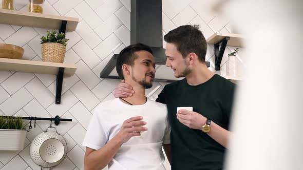 Young Male Gay Couple Hugging Each Other Drinking Morning Coffee alt