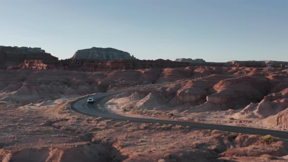 Drone Following Vehicle with Tourists Traveling Famous Goblin Valley at Sunrise alt