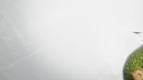 Ripe Green Zucchini Falls Down Into Clear Water with Tomato alt