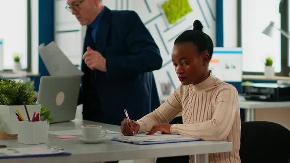 African Businesswoman Analysing Report and Looking at Camera Smiling alt