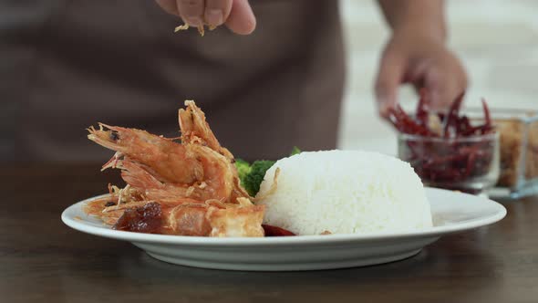 Chef seasoning deep fried prawns in tamarind sauce with rice