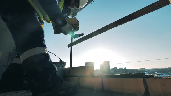 Construction Worker at a Construction Site. Bricklaying Is Being Carried Out By a Male Constructor alt