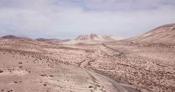 Path road in the middle of a mountains sand desert with blue bright sky in background. Arid climate alt