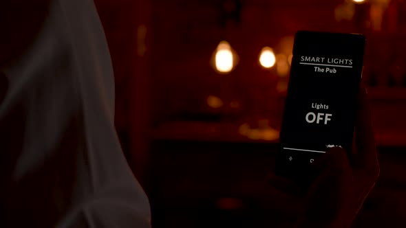 Dolly Close Up Shot of Bartender Using a Voice Activated App To Turn ON the Lights alt