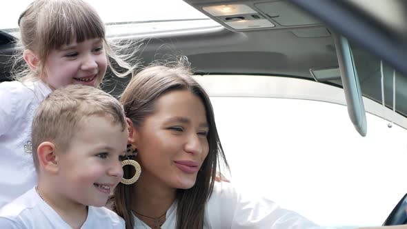 Happy family with daughter and son taking selfie in car alt