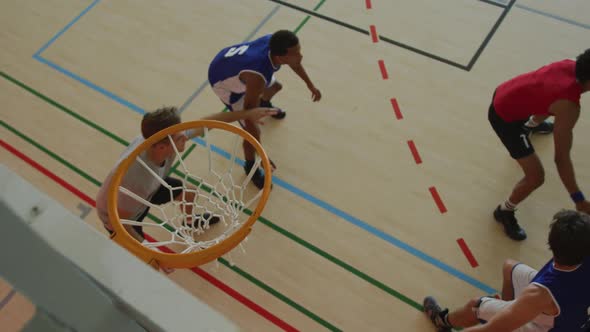 Overhead view of african american male basketball player scoring goal against diverse players alt